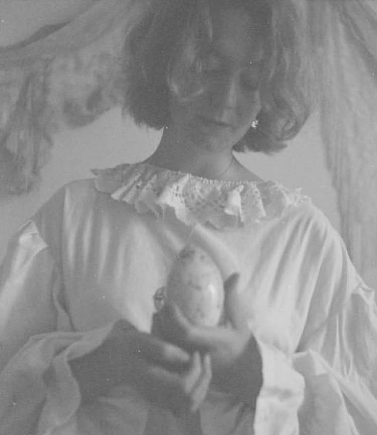 Artistic photo of Nooka Shepherd, a member of the editorial board. She is wearing a white tunic and cradling a potato.