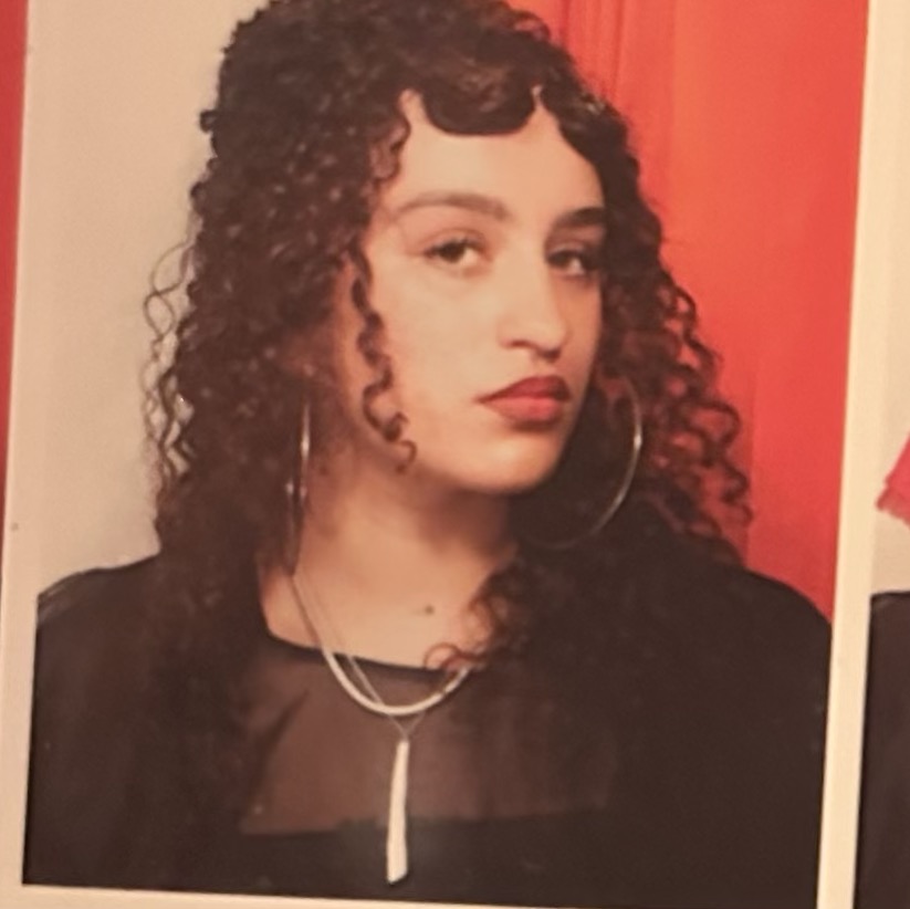 Headshot of Nya Furber, a member of the editorial board. She is wearing a black top with a white necklace and large hoop earrings.